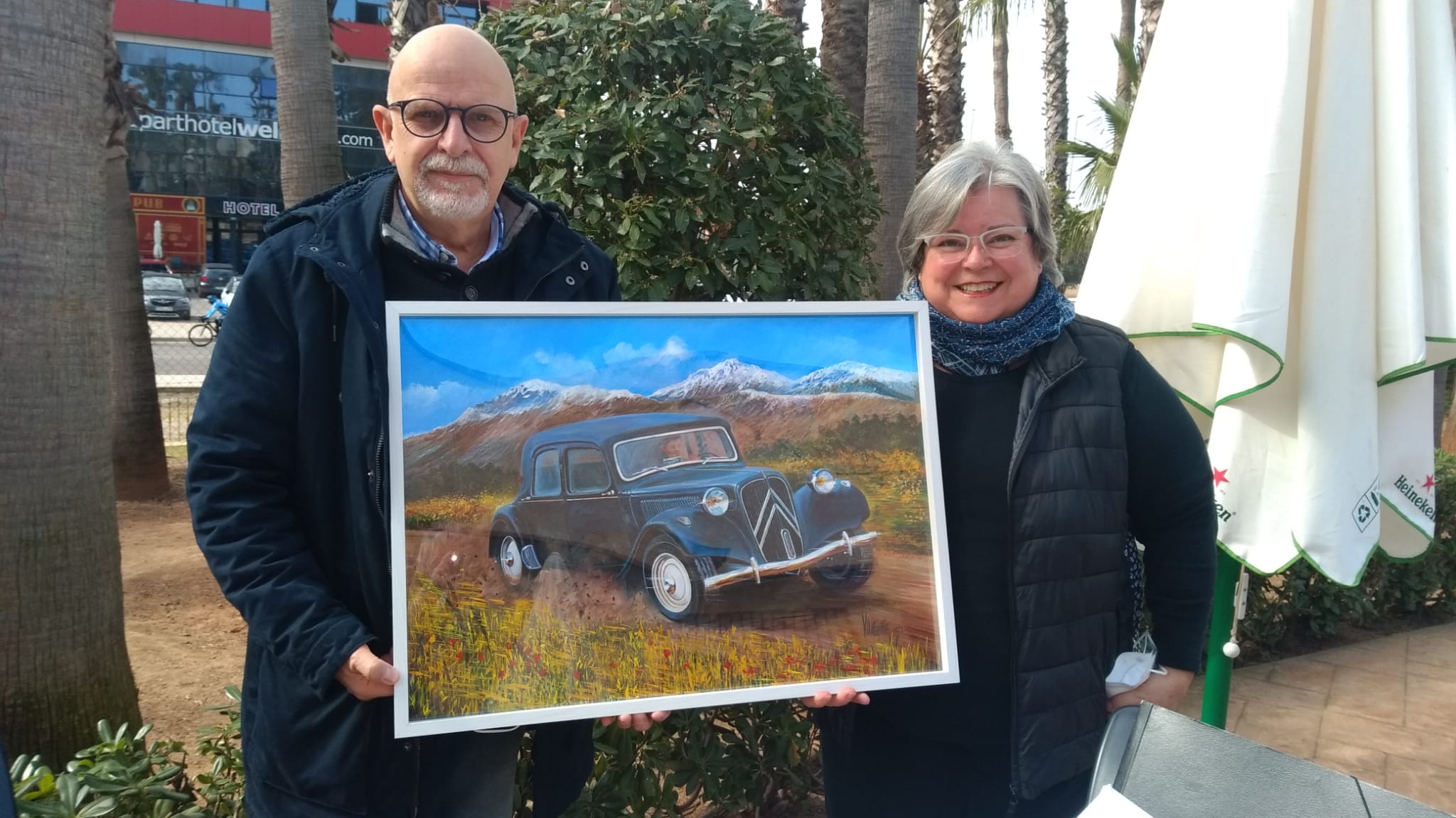 EL PINTOR JOSÉ MARÍA VILLAFUERTE Y LA PROMOTORA DEL CITRONEROS CLUB VALENCIA YANELA GIL CON EL CUADRO QUE SE SORTEARÁ EN EL RACING LEGENDS 2022